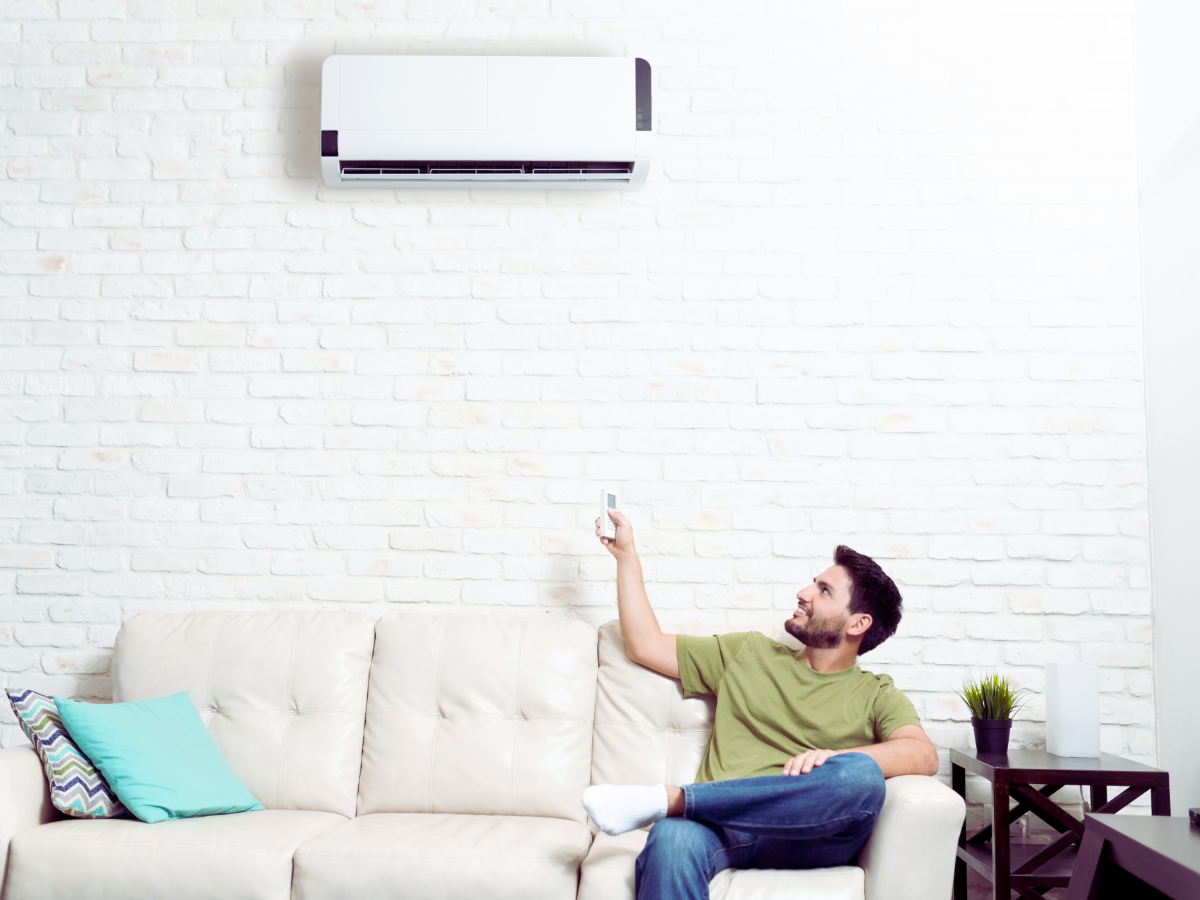 man on his couch turning on his mini split ductless ac system