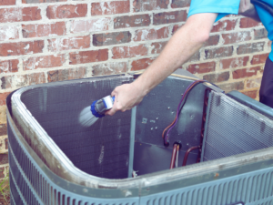 Man washing heat pump coils with hose