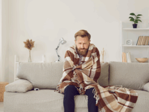 Cold homeowner wrapped in blanket because furnace keeps turning off